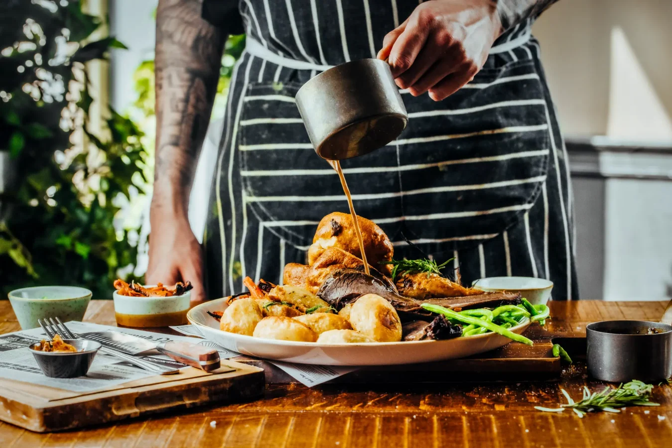 Chef pouring gravy over a Sunday roast with Yorkshire pudding and roast potatoes at The Hercules Pillars