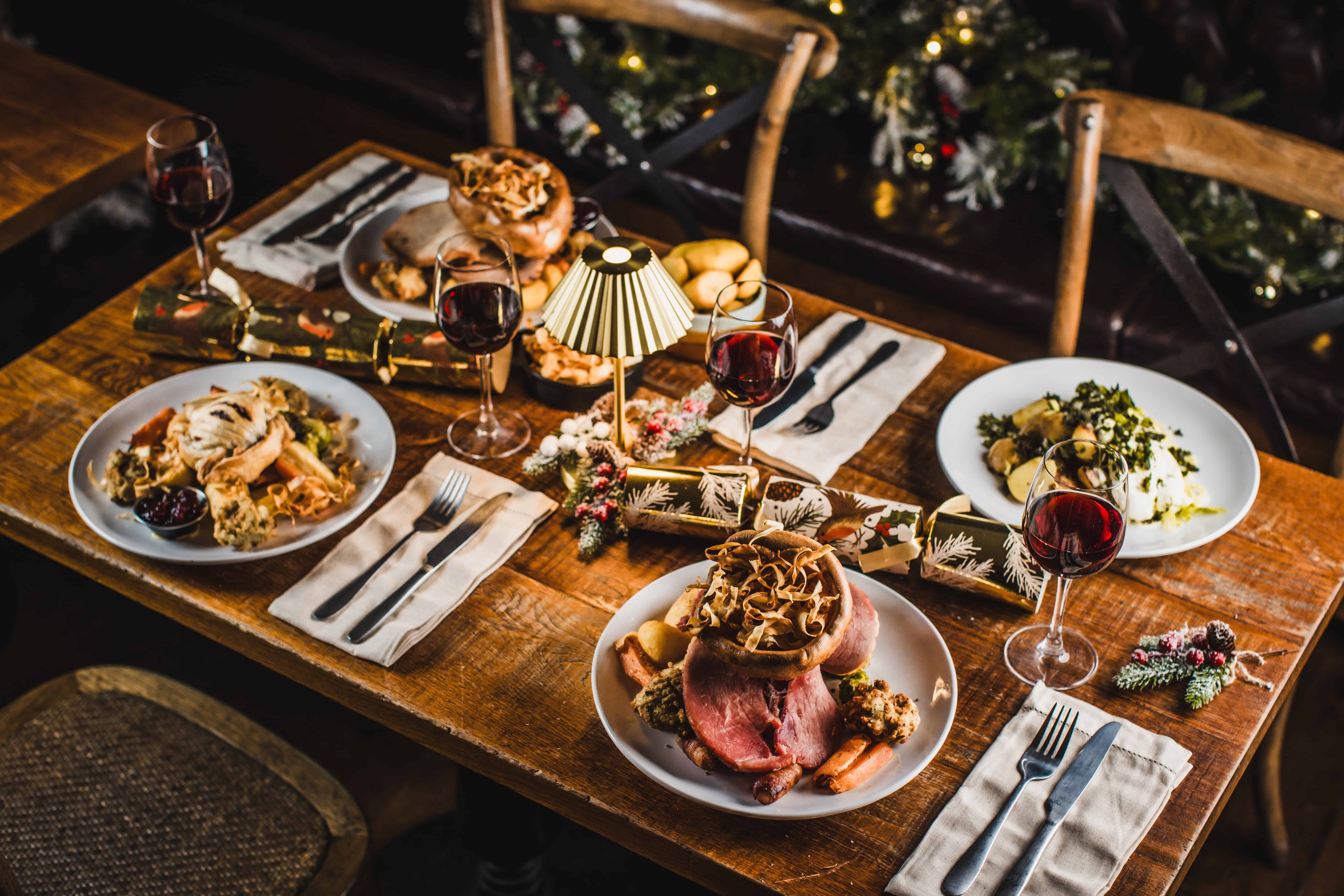 Festive Christmas dinner table with roast beef, pasta, and wine glasses.