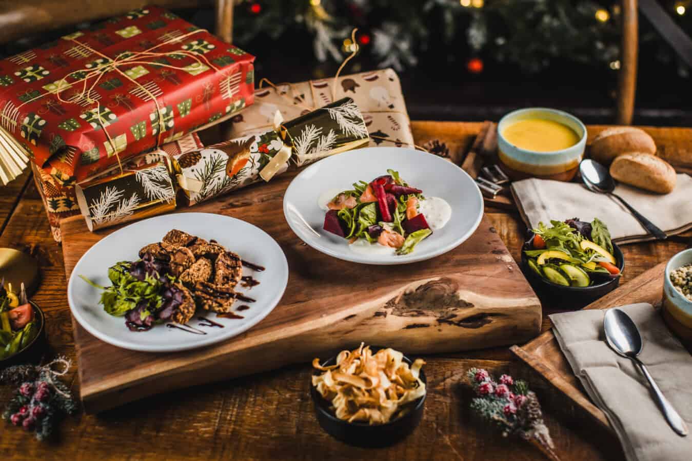 Festive Christmas meal with salads, bread, and desserts on a wooden table.